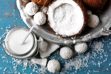 Homemade candies in coconut flakes and ingredients on color wooden background