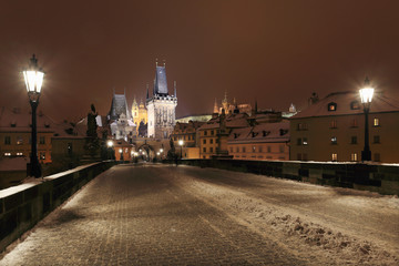 Night snowy Prague gothic Castle, Bridge Tower and St. Nicholas' Cathedral from Charles Bridge with its Statues, Czech republic