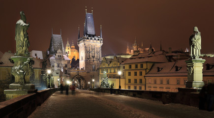 Fototapeta premium Night snowy Prague gothic Castle, Bridge Tower and St. Nicholas' Cathedral from Charles Bridge with its Statues, Czech republic