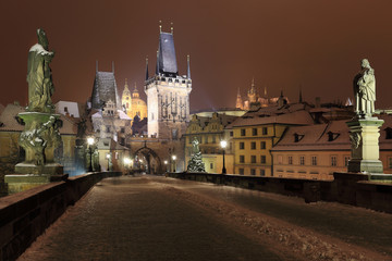 Night snowy Prague gothic Castle, Bridge Tower and St. Nicholas' Cathedral from Charles Bridge with its Statues, Czech republic