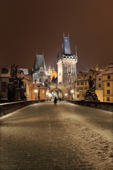 Fototapeta premium Night snowy Prague with Bridge Tower, St. Nicholas' Cathedral and gothic Castle from Charles Bridgel, Czech republic