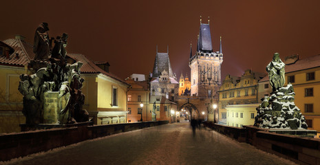 Night snowy Prague with Bridge Tower, St. Nicholas' Cathedral and gothic Castle from Charles Bridgel, Czech republic