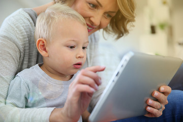 Mother and baby son playing with digital tablet