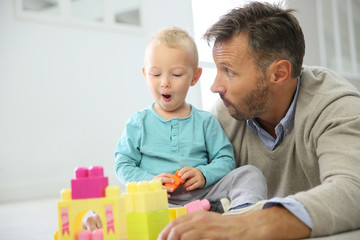 Obraz premium Daddy with baby boy playing with blocks on the floor