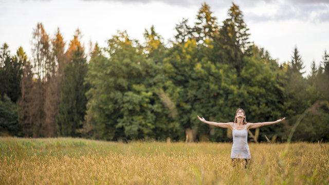 Young woman standing in the middle of autumn meadow with high go