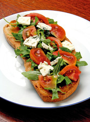 Bruschetta with tomatoes and gorgonzola cheese served with fresh rocket leaves.