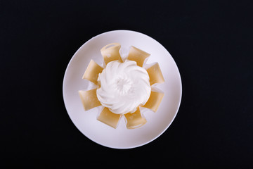 creamy white cheese on a white plate with a black background, top view, low-calorie dairy product