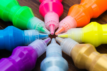 Bottles with colorful dry pigments on wooden background