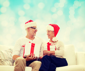 happy senior couple in santa hats with gift boxes