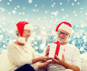 happy senior couple in santa hats with gift box