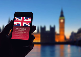 Hand holding smartphone with London city background.