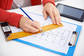 Close-up of woman architect drawing and measuring construction plan in her office. Woman designer...