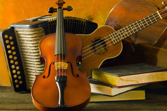 A still-life backdrop of violin, guitar and books with wooden background