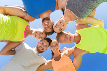 group of happy sporty friends in circle outdoors