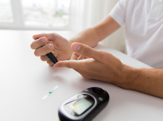 close up of man checking blood sugar by glucometer