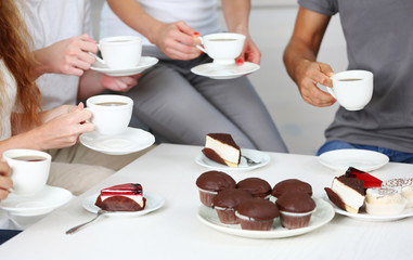 Friends hands with desserts and cups of tea, close up