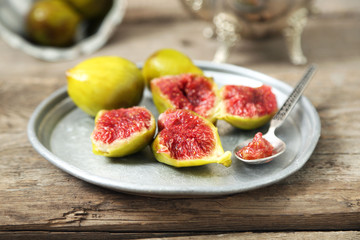 Ripe figs on tray, on wooden background