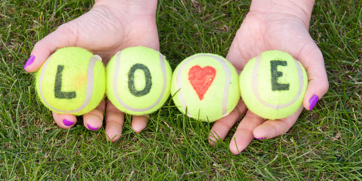 Tennis balls with word love and love heart held by woman