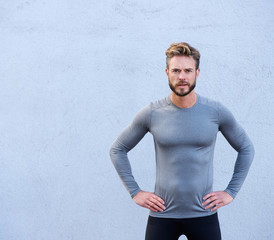 Serious fitness trainer standing against gray background