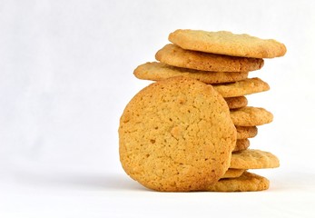 Staggered stack of homemade peanut butter cookies with one resting against it. On a white...