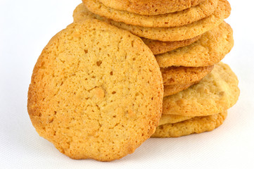 Close up stack of homemade peanut butter cookies with one resting against it. On a white background.