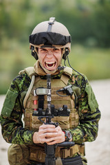 Canadian soldier yelling and pointing a rifle at the camera.Bad