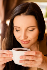 Charming young woman enjoying aroma coffee in cafe