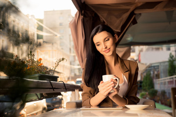pretty girl sitting in a cafe on the terrace with a cup of coffee