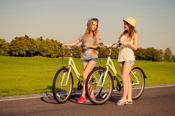 Two shapely girls together   walking with a bicycle