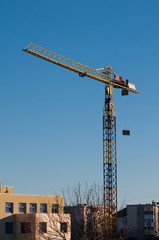 Fototapeta na wymiar yellow crane lifting materials on building site, vertical view