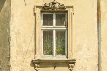 Fototapeta na wymiar A window in an old house. Authentic wooden window frame. Stucco. Vintage wallpaper