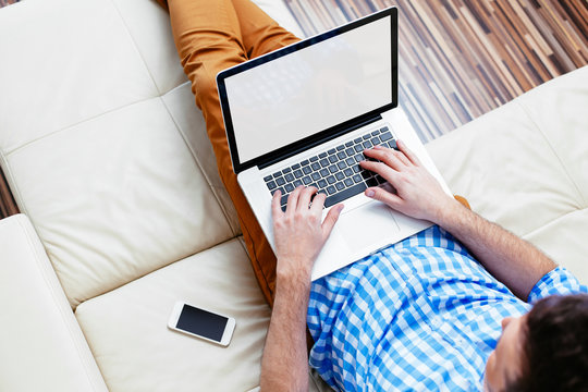 Man sitting on a sofa and browsing the web. Connecting with the world