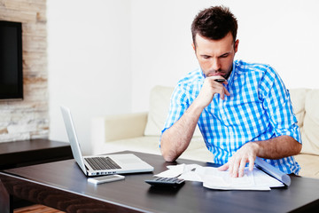 Young man paying bills at home