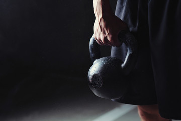 Strong hand holding a black kettlebell