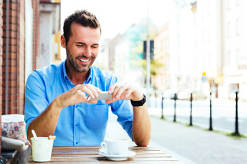 Young man taking picture of coffee cup at cafe