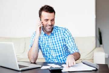 Young man talking on the phone and calculating