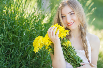 Closeup portrait of cute young girl with yellow flowers smiling outdoors 