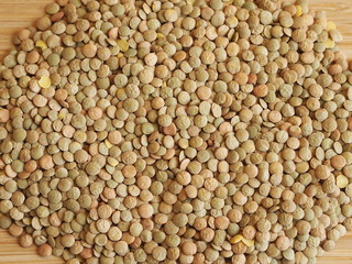 Heap of lentil seeds on a wooden background.