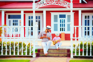 father and son playing music, sitting on stairs