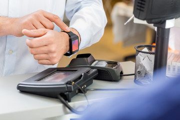 Customer Paying Through Smartwatch At Counter In Pharmacy