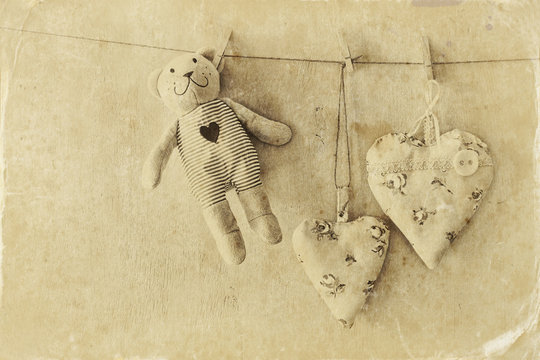 teddy bear and fabric hearts hanging on rope. retro filtered image. old style photo
