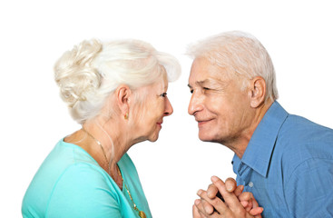  Seniorenpaar schaut sich verliebt in die Augen mit verschränkten Händen auf weißem Hintergrund   