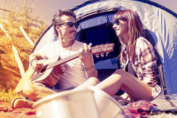 couple of young lovers enjoy playing guitar at the campsite