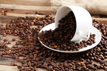 Coffee beans in cup on a brown wooden background