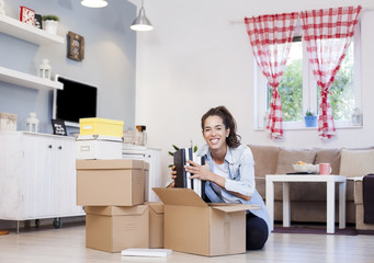 Happy girl packing cardboard boxes moving to new house