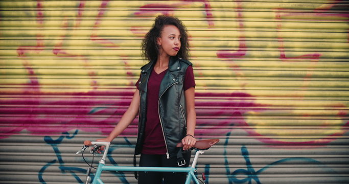 African American teen girl with her bicycle on a sidewalk