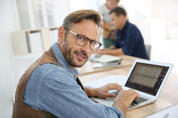 Portrait of trendy man working on laptop computer