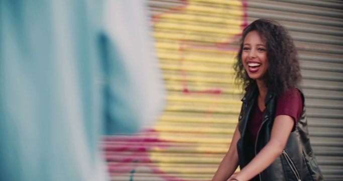 Girl smiling at a friend with urban graffitti behind her