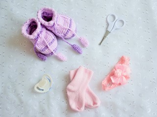 Collection of baby things, top view. Booties, pacifier, socks, bow, scissors on white background.
