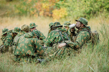 soldiers team are heated food on the fire and eat in the forest